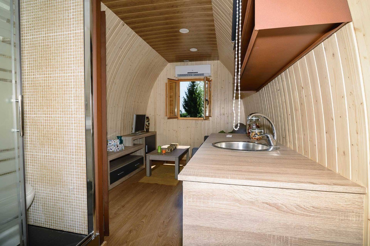 Cocina y salón integrados en el interior de un Maxicozy con panelado de madera